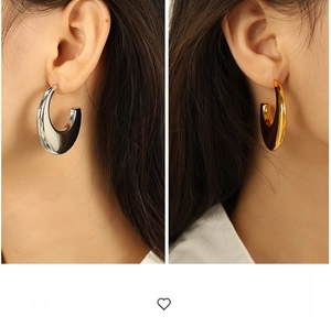 Macro detail of oversized gold and silver C-shaped earrings with high polish finish