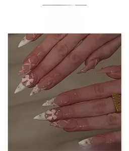 Detailed view of pink stiletto press-on nails with 3D bows, flowers and ribbon patterns