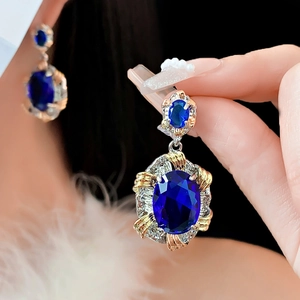 Macro shot of vintage style earrings with oval blue zircon and gold-silver metalwork