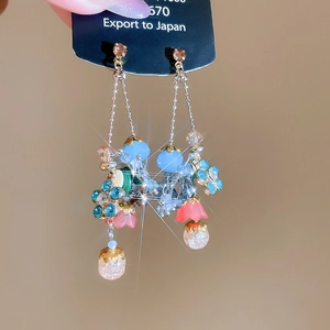 Detail of bohemian drop earrings with colorful beads and leaf charms held by hand