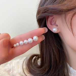Detailed comparison of various pearl stud sizes from small to large on model ear and hand