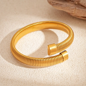 Macro shot of golden Tubogas spiral bracelet featuring polished ends and metallic texture