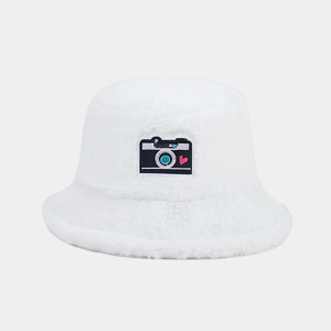 Detailed view of white fuzzy bucket hat with camera patch and red heart embroidery