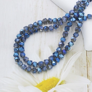 Detailed view of 6mm faceted dark blue crystal glass beads on light wood surface