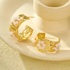 Detail view of 18K gold C-shaped earrings with hammered texture and pink floral beads