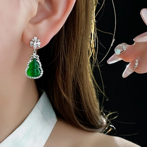 Close-up of a green gourd resin earring with zircon details worn on a female model