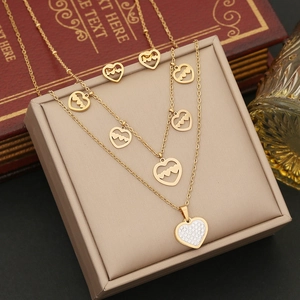 Détail de parure collier double cœur doré et boucles d'oreilles avec cristaux clairs