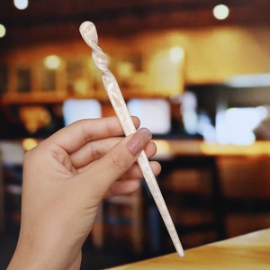 Close-up of elegant cream marble acetate hair stick with a stylish twisted design