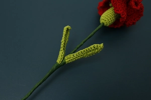Detailed close-up showing the handmade crochet texture of red carnation yarn flower