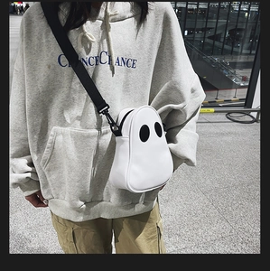Street style view of the white ghost shaped crossbody bag with black nylon strap
