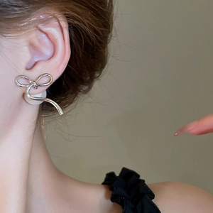 Detailed close-up of bow knot pearl earrings on model with 14K gold plating texture