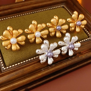 Detail view of 18k gold plated flower earrings with pearls on dark wood vintage frame