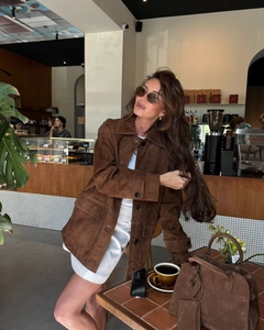 Detailed close-up of brown faux suede jacket with classic collar in cozy cafe setting