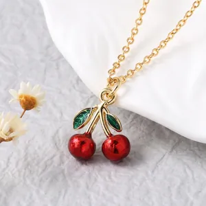 Detailed close-up of a red cherry enamel pendant on a delicate gold-plated chain