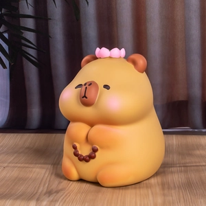 Détail macro de la tirelire Capybara zen avec lotus et chapelet sur une table en bois