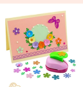 Macro shot of a pink flower paper punch tool with colorful cutout cards and floral crafts