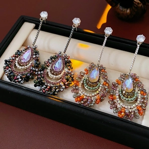 Detailed view of silver needle drop earrings with iridescent gems in a black jewelry box