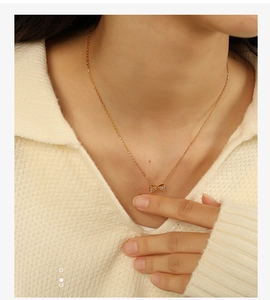 Vue détaillée d'un collier nœud doré orné de cristaux pavés porté par un mannequin