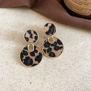 Detail of round leopard print earrings with golden frames in a vintage design