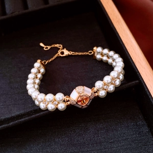 Double-layered pearl bracelet with gold chain featuring orange gemstone and shell inlay