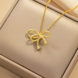 Golden bow pendant necklace with sleek snake chain displayed in a beige jewelry gift box