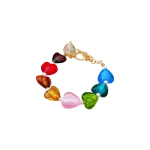 Colorful glass heart and pearl beaded bracelet with a gold OT clasp on white background