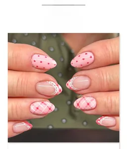 Detail of pink strawberry style almond press-on nails with dot and lace patterns