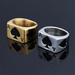 Detail of Ace of Spades poker rings in gold and silver finishes on black mirror surface