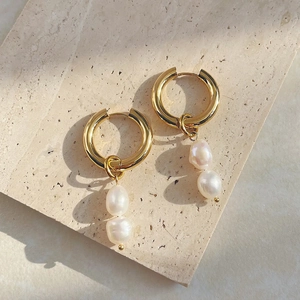 Detail of elegant gold hoop earrings with natural baroque freshwater pearls on stone