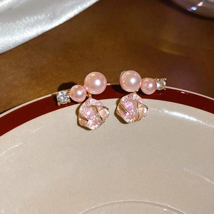 Vista macro di orecchini a fiore con perle rosa e strass su un piatto di ceramica