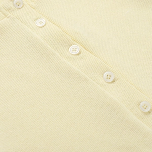 Vista dettagliata del cardigan in maglia gialla con bottoni bianchi e texture