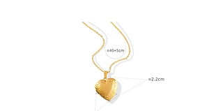 Detail of vintage 18K gold heart locket pendant featuring classic floral scroll engraving