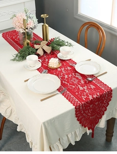 Close-up of red lace Christmas table runner with festive hollow-out floral lace patterns