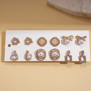 Close-up of elegant 6-pair gold earring set with rhinestones and faux pearls on a card