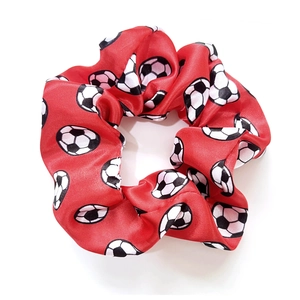 Red satin scrunchie with football patterns shown on white background in top view