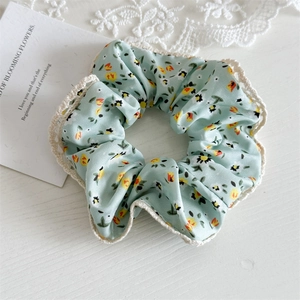 Detail of floral scrunchie in mint green with delicate crochet lace edging on wood