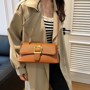 Close-up of brown textured leather bag featuring a polished gold square buckle detail