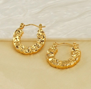 Macro detail of 18K gold plated hoop earrings featuring a vintage hammered lava texture