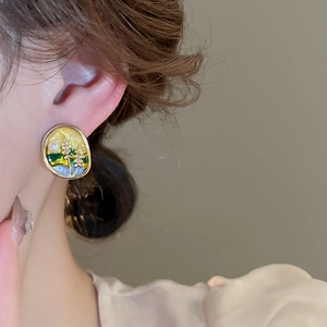 Gros plan d'une boucle d'oreille ovale rétro avec peinture à l'huile et bord doré