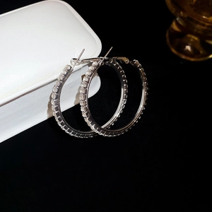 Macro shot of silver crystal hoop earrings leaning on a white leather jewelry box