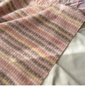 Close-up of rainbow plaid scarf with pink and yellow fringe and soft wool texture