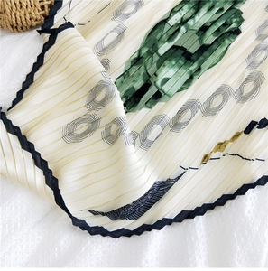 Dettaglio foulard di seta plissettato con stampe di foglie e bordi ondulati neri