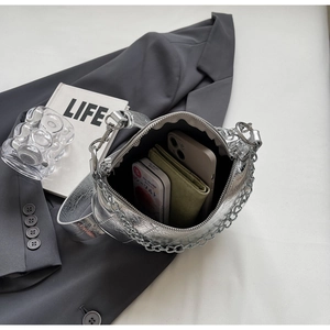Top view of silver dumpling bag showing interior capacity on a grey suit with accessories