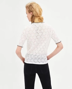 Dettaglio retro del top in pizzo bianco con bordi smerlati neri su colletto e polsini