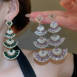 Detailed close-up of emerald and lavender fan-shaped pendant earrings with tassels