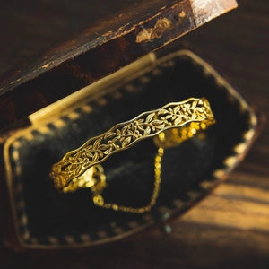 Macro shot of gold vintage hollow vine floral bracelet with secure thin safety chain
