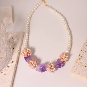 Freshwater pearl necklace with amethyst and pink woven floral beads on marble