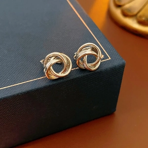 Gros plan de boucles d'oreilles nœuds dorés torsadés sur un écrin bleu marine chic