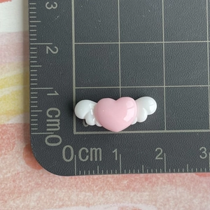 Detailed view of pink resin heart with white wings on measuring mat showing 2.5cm size