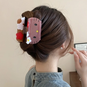 Detail view of acrylic cat hair claw clip on model's head with floral embellishments